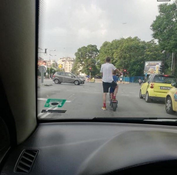 Мъж вози дете на тротинетка в трафика. Там ли им е мястото? СНИМКИ
