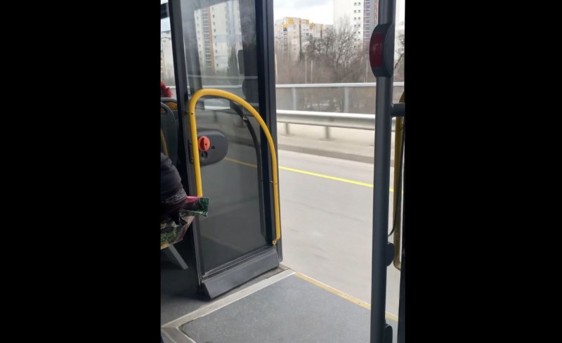 Пътнически автобус, превозващ пътници, се движи с отворени врати. Тази
