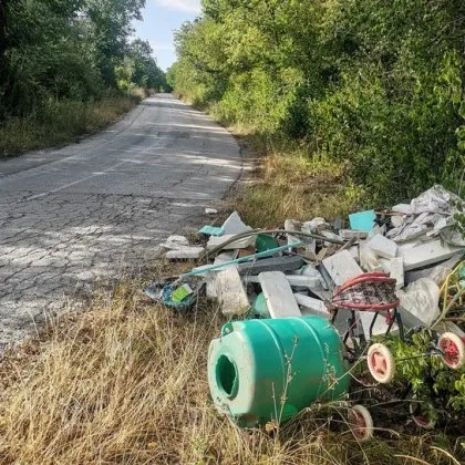 Сив поочукан път красива природа и огромна купчина със смет Тази