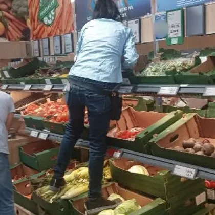 Жена стъпка с обувки зеленчуци в супермаркет, за да стигне до висок рафт СНИМКА