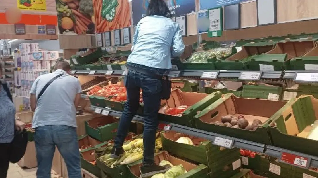 Жена стъпка с обувки зеленчуци в супермаркет, за да стигне до висок рафт СНИМКА