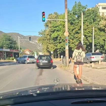 Жена подкара тротинетка по улица, дете се държи за крака ѝ СНИМКА