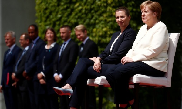 Меркел слуша химна седнала, промениха протокола заради нея