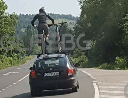 Безразсъдно! Мъж яхна колело върху тавана на движещ се автомобил СНИМКА